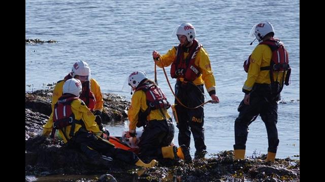 Crew members in lifeboat PPE taking part in training on a beach