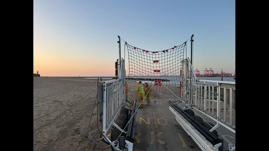 Sunset on New Brighton beach, with orange, pink and golden sky in the background. In the foreground, the recovery carriage can be seen with fully rigged recovery net.
