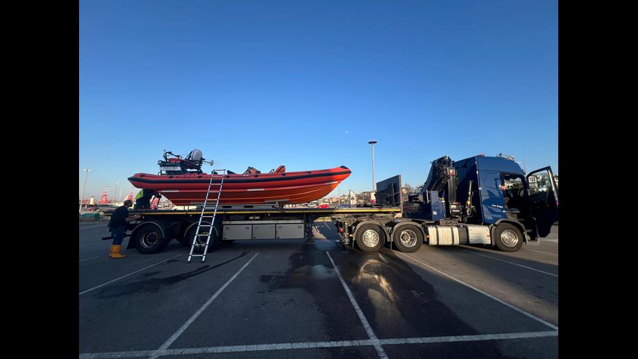 New Brighton RNLI's volunteer crew work, with the help of a ladder, to remove all necessary equipment from the lifeboat. Full side on view of the relief craft on the back of the road transport.
