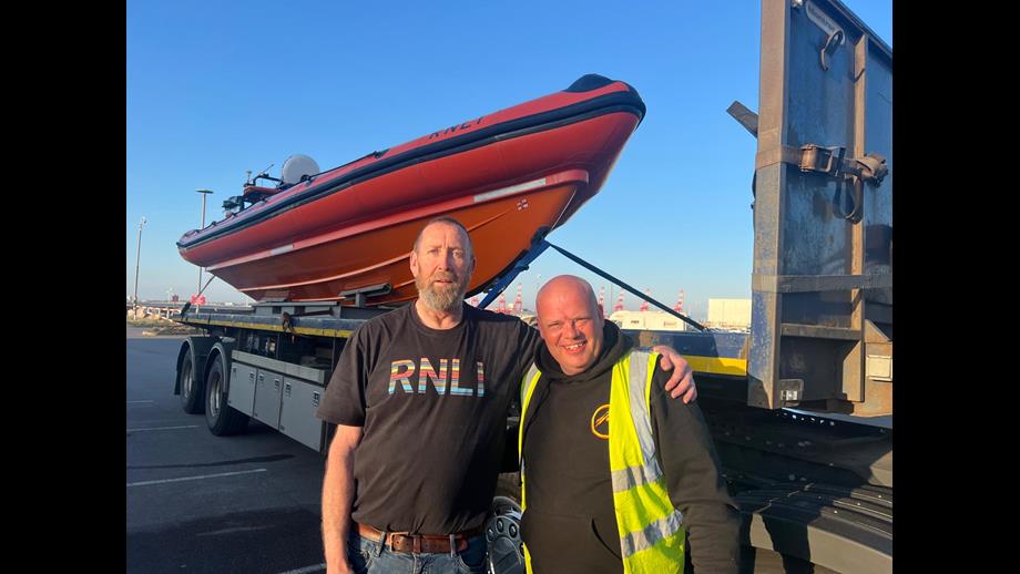 Mike Jones and Jason pose in front of the relief craft, sat on the back of the flat bed transport truck.
