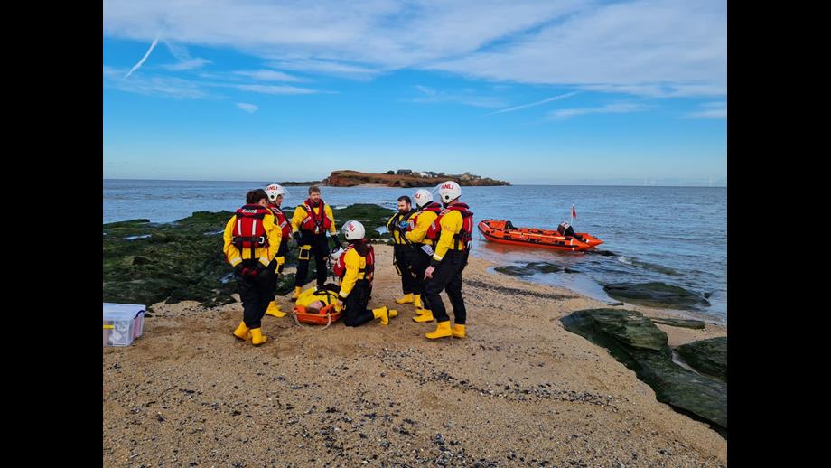 RNLI crew can be seen performing first aid training with the D class in the background