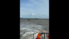 The photo shows the dredger being pulled away from the shore by the RNLI shannon lifeboat