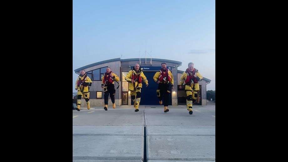 5 memebers of Wells RNLI crew running in full lifeboat kit down the slip way at Wells station responding to Mayday mile fundraising call