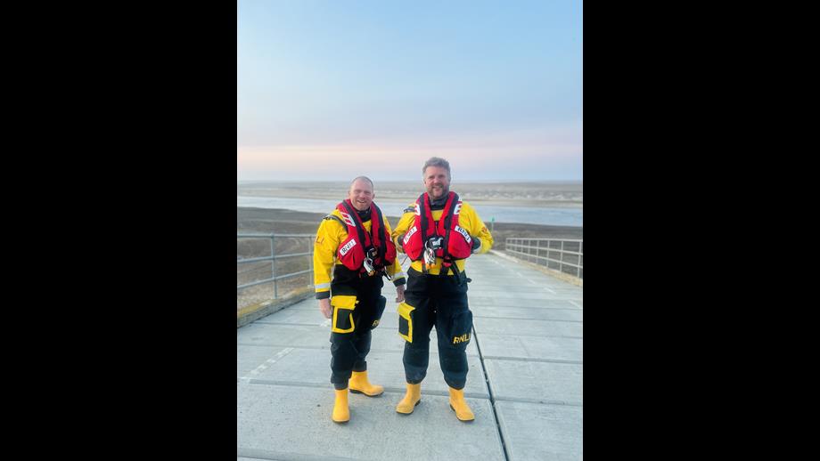 Andy and Gary Wells RNLI volunteer crew at Wells in full lifeboat kit on the slipway at the station with beach in the background