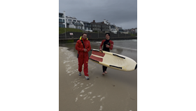 RNLI lifeguards Cameron Leighton &amp; Ethan Hill returning from the sea after assisting five children caught by offshore winds, out at sea