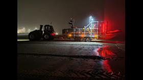 A dark night image, with New Brighton's tractor, carriage and lifeboat making their way to the launch site. Red and white lights shine on the slight fog.
