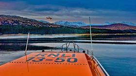 The coastguard helicopter in a darkening sky against the hills in a photo taken from the stern of the lifeboat