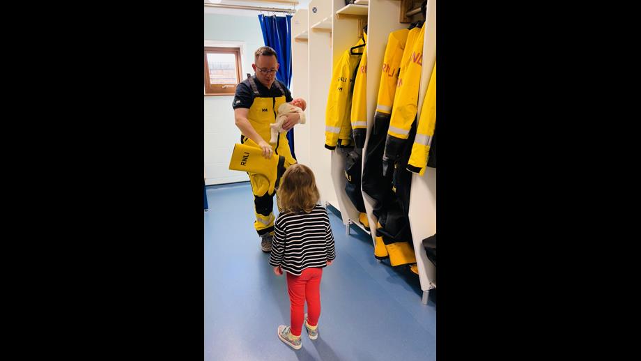Photo shows volunteer crew member Gerwyn in his RNLI yellows, showing his young daughter and baby son his yellow wellies