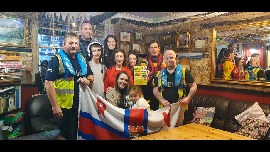 The Cass family and Cowes RNLI volunteers pose for a celebratory photo inside The Duke of York.