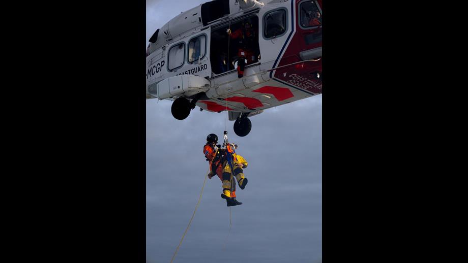 two people hanging from helicopter