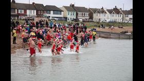 Photo of December Dip participants running into the sea. 