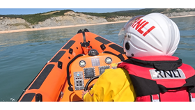 Photo shows lifeboat helm steering the inshore lifeboat towards the beach