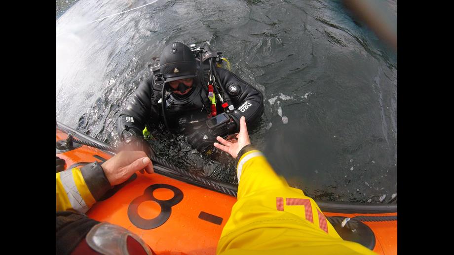 RNLI crew reach out to assist a diver from the water onto the lifeboat