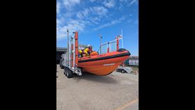 Orange lifeboat preparing to launch with crew members in bright yellow RNLI dry suits