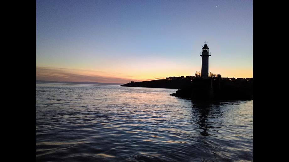 The photo shows the lighthouse at the entrance to the outer harbour as the sun set.