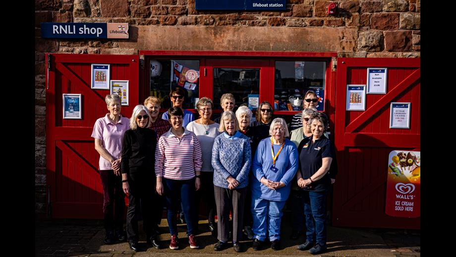 Fourteen women outside shop.