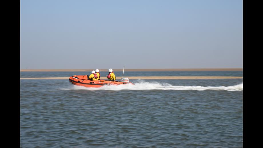 Wells RNLI D class lifeboat on cut off by tide rescue with crew of three on open water sunny weather
