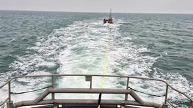 tow line from bow of the lifeboat to small fishing boat in the distance