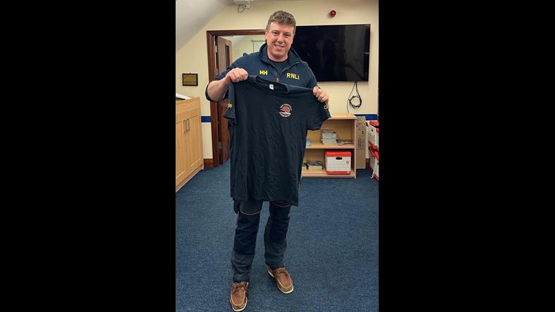 Resilience Coxswain/Mechanic Thomas Davis holding up a Aran Islands crew tshirt
