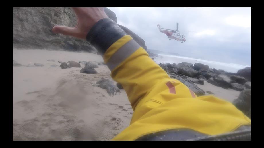 Helicopter taking off from small beach area.