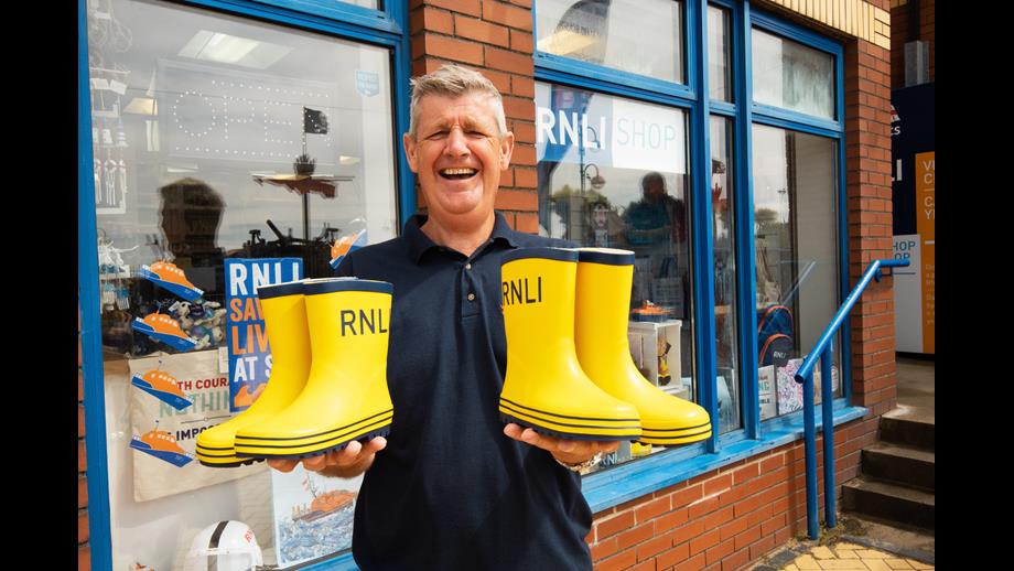 A RNLI shop volunteer holding some RNLI boots