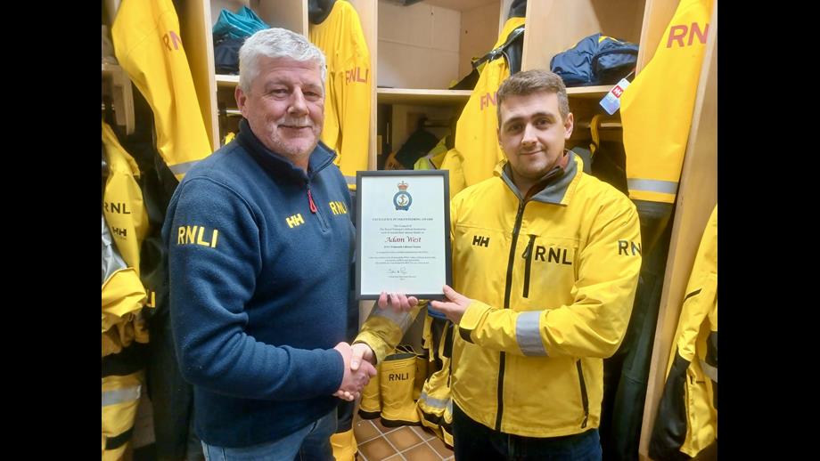 Adam West being presented with his Excellence in Volunteering Award framed certificate by Coxswain Jonathon Blakeston