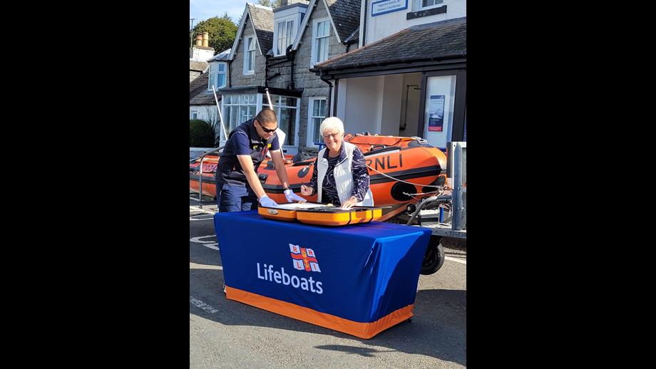 Myrna Robertson signs the 200 scroll at Kippford Lifeboat Station
