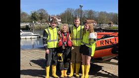 Mother in RNLI kit with three children in front of D Class lifeboat