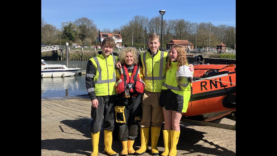 Mother in RNLI kit with three children in front of D Class lifeboat