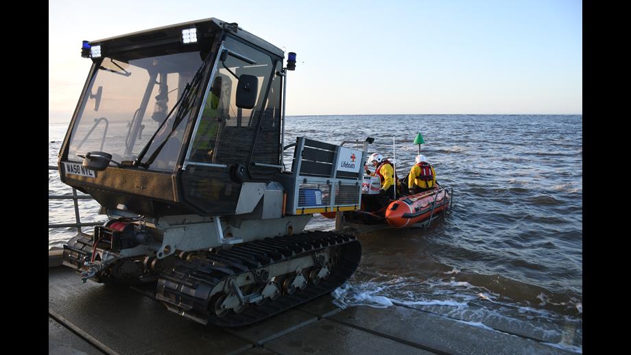Wells RNLI Inshore lifeboat and SoftTrak launching from slip way with a crew of three