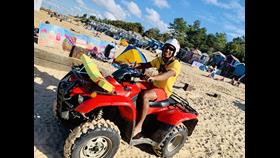 RNLI Lifeguard Harry Yarbo on Wells beach in full lifeguard uniform and with quad bike