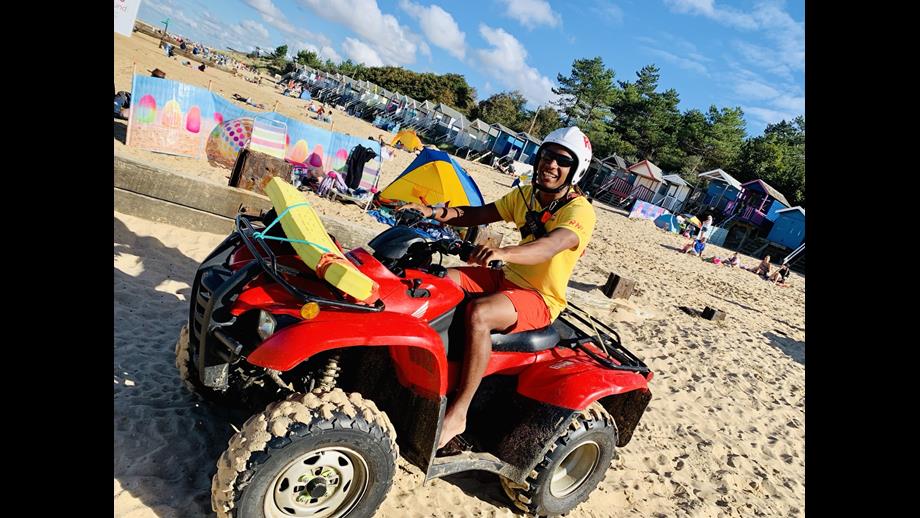 RNLI Lifeguard Harry Yarbo on Wells beach in full lifeguard uniform and with quad bike