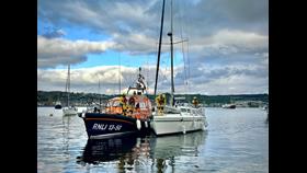 A white yacht with the Shannon class lifeboat in a calm reflecting sea with Oban in the background