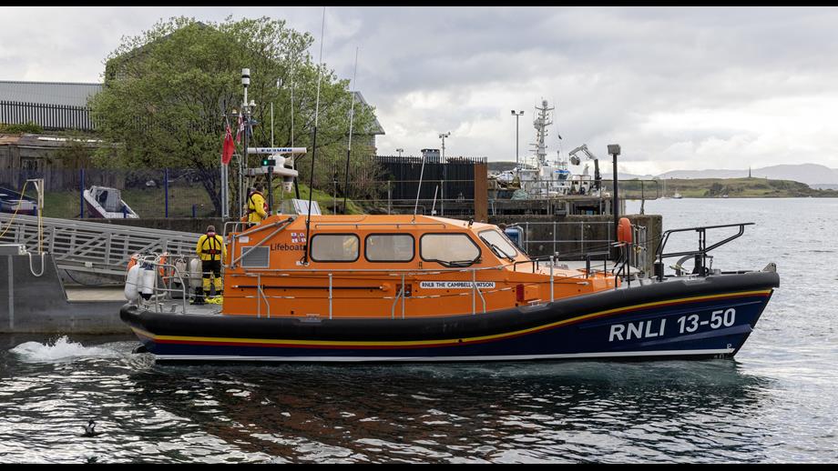 The Shannon class lifeboat manoeuvring close to the pontoon with the yellow-clad crew working to secure the vessel
