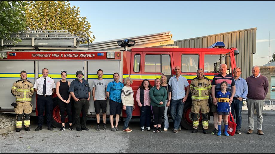 RNLI volunteers and firefighters standing in a row outside in front of a fire truck