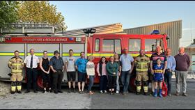 RNLI volunteers and firefighters standing in a row outside in front of a fire truck