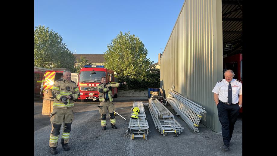 Two firefighters in their kit and their fire chief in formal uniform preparing to talk to RNLI volunteers ahead of a practical demonstration outside