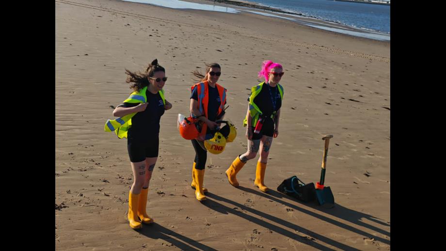 New Brighton RNLI's all-female shore crew carry various pieces of equipment across the beach.
