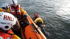 Exercise between Scarborough D-class inshore lifeboat and lifeguards. Lifeguard supporting casualty in the water.