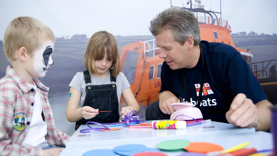 Education volunteer with a young boy and girl participating in a colouring book activity at Legoland