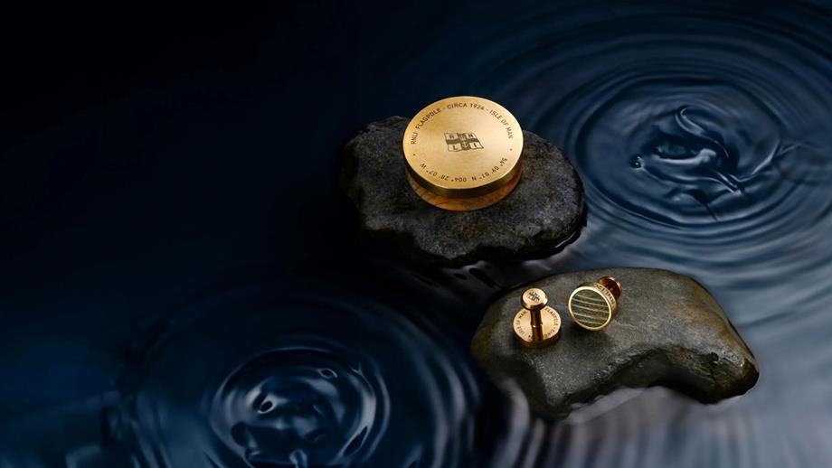 The RNLI 200 Limited Paperweight and RNLI 200 Limited Cufflinks on separate rocks, surrounded by water
