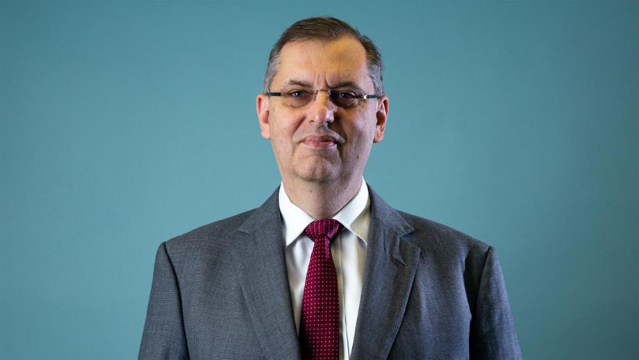 Headshot of Denis Woulfe against blue background