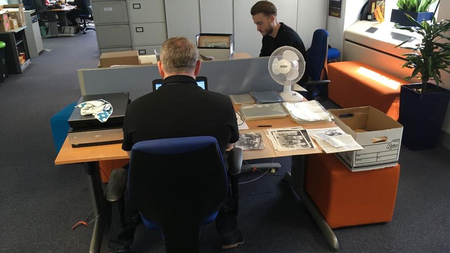 Colour image of two student volunteers cataloguing and digitising photographs 