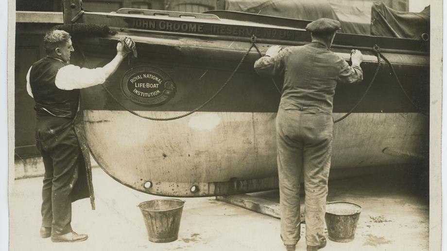 Black and white image of workmen cleaning lifeboat