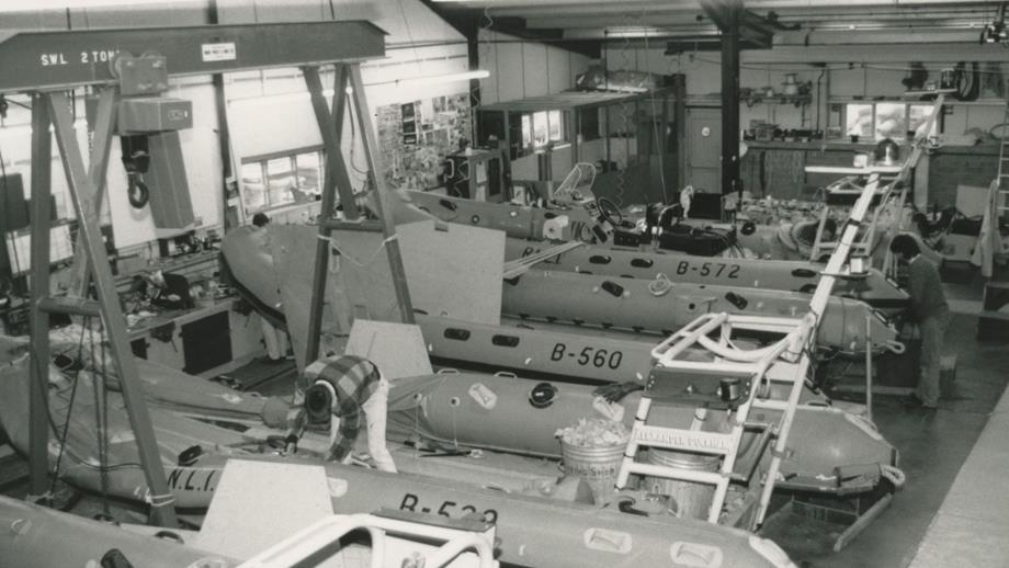 Black and white image of workshop interior with inflatable lifeboats being manufactured