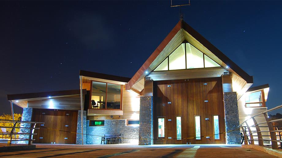 A view of Exmouth Lifeboat Station at night. The view is from the slipway, looking up towards the large boathouse doors where the Shannon class lifeboat is housed. A light can be seen in the window to the left of these doors, where the crew room and office is situated.