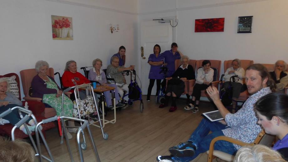 Colour photograph of a group of care home residents in photo reminiscence session