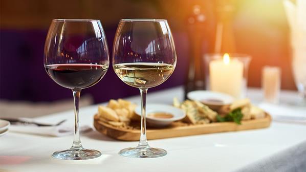 Two glasses of wine standing on a table with candle in the sun light