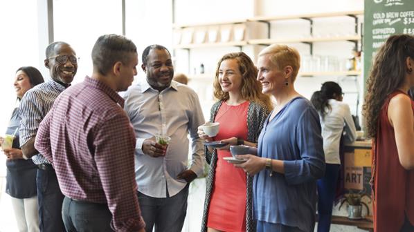 Five people standing in a group talking casually
