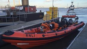 Small orange lifeboat in waterside moorings.